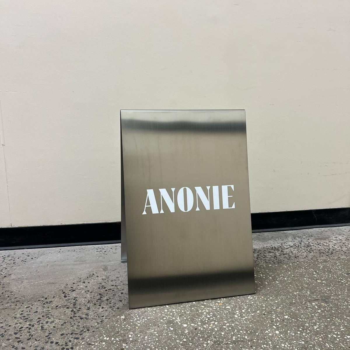 Small mirrored A-frame sign with white Anonie lettering.