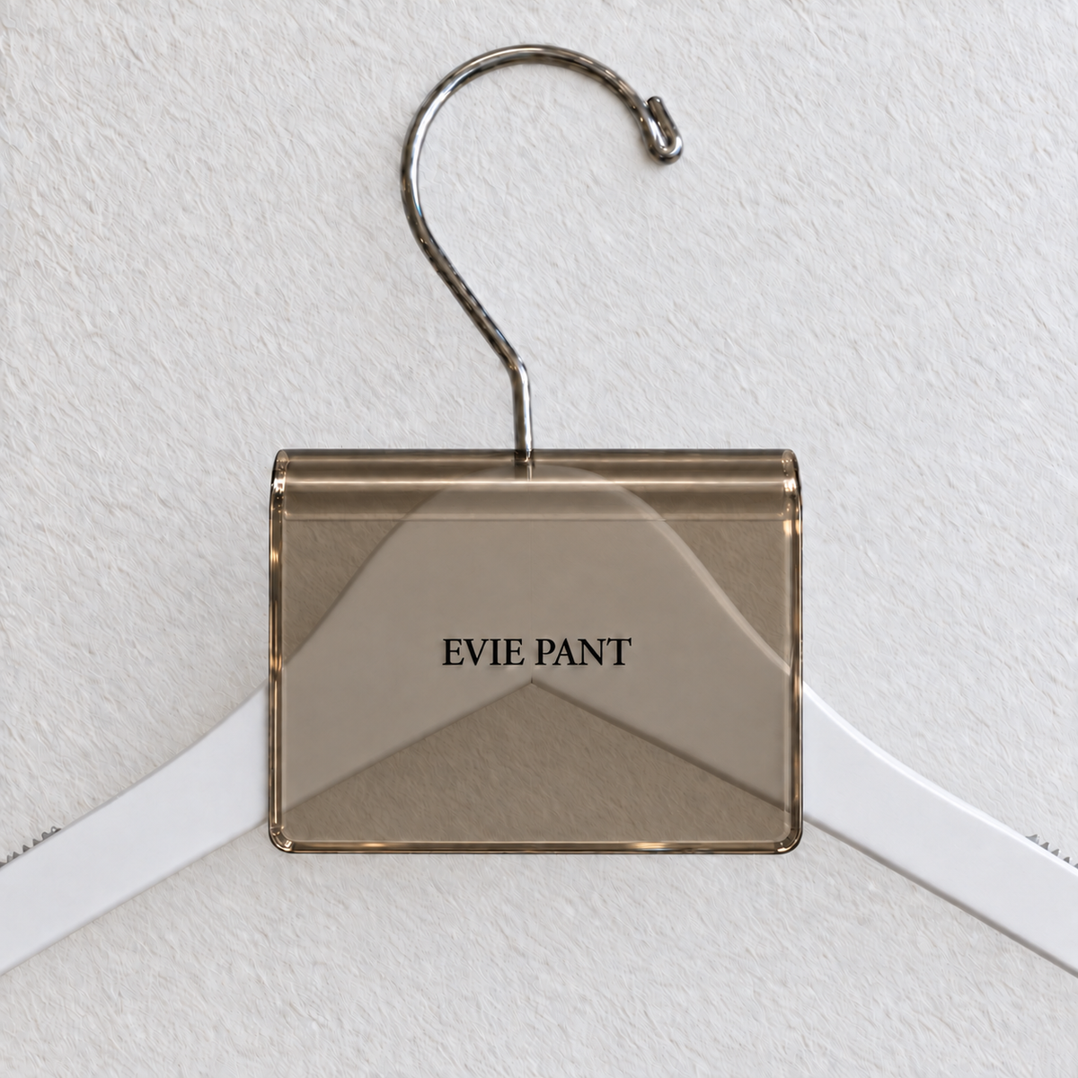 Bronze Smoke acrylic hanger sign clip resting on the rounded crown of a white wooden hanger, with example EVIE PANT print