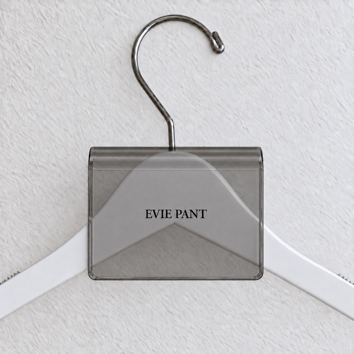 Gray Smoke acrylic hanger sign clip with soft edge reflections, resting on a white wooden hanger, with example EVIE PANT print