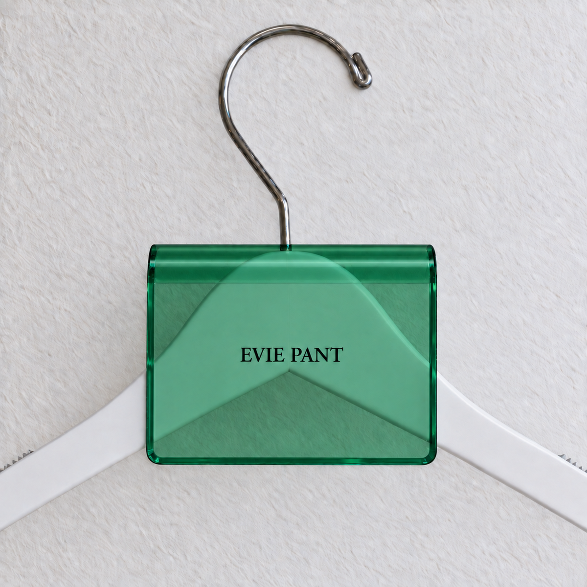 Green transparent acrylic hanger sign clip with soft edge reflections, resting on a white wooden hanger, with example EVIE PANT print