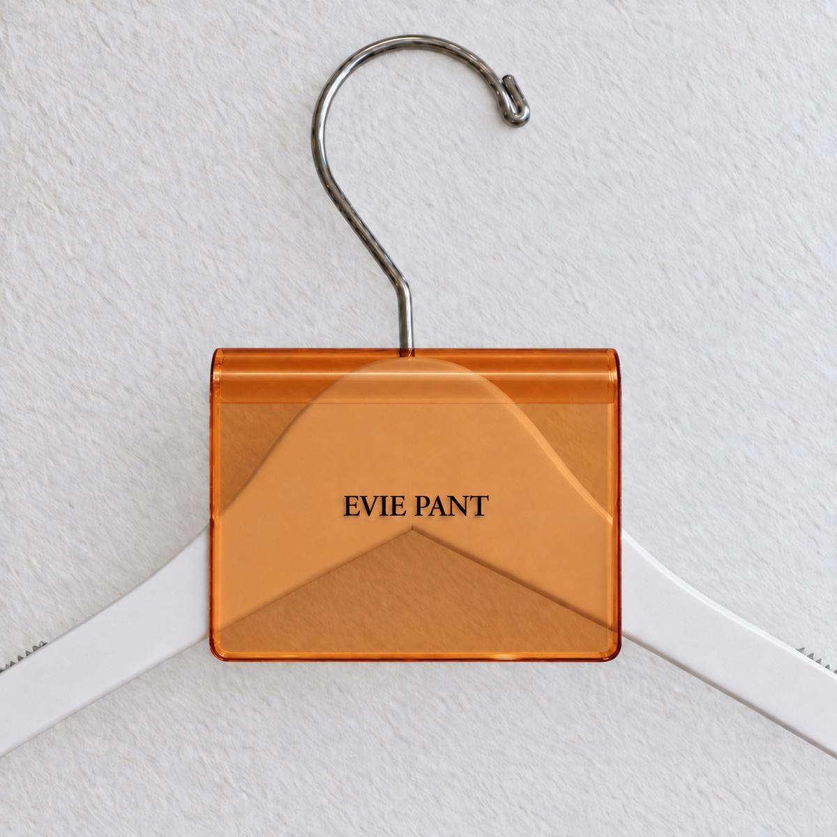 Orange transparent acrylic hanger sign clip with soft edge reflections, resting on a white wooden hanger, with example EVIE PANT print