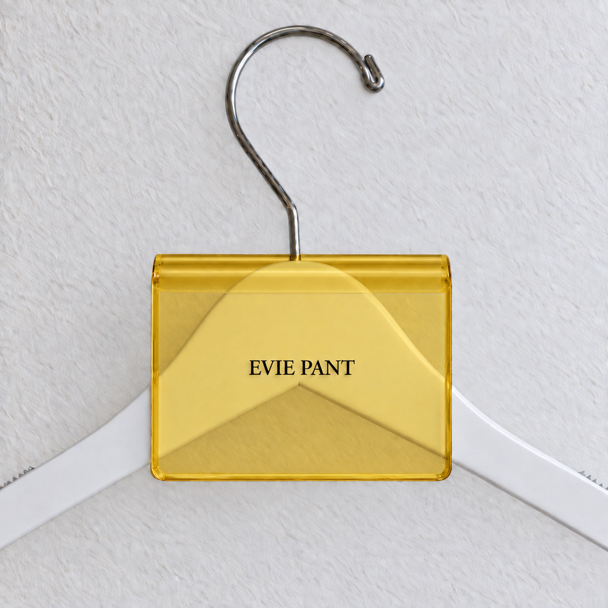 Yellow transparent acrylic hanger sign clip with soft edge reflections, resting on a white wooden hanger, with example EVIE PANT print