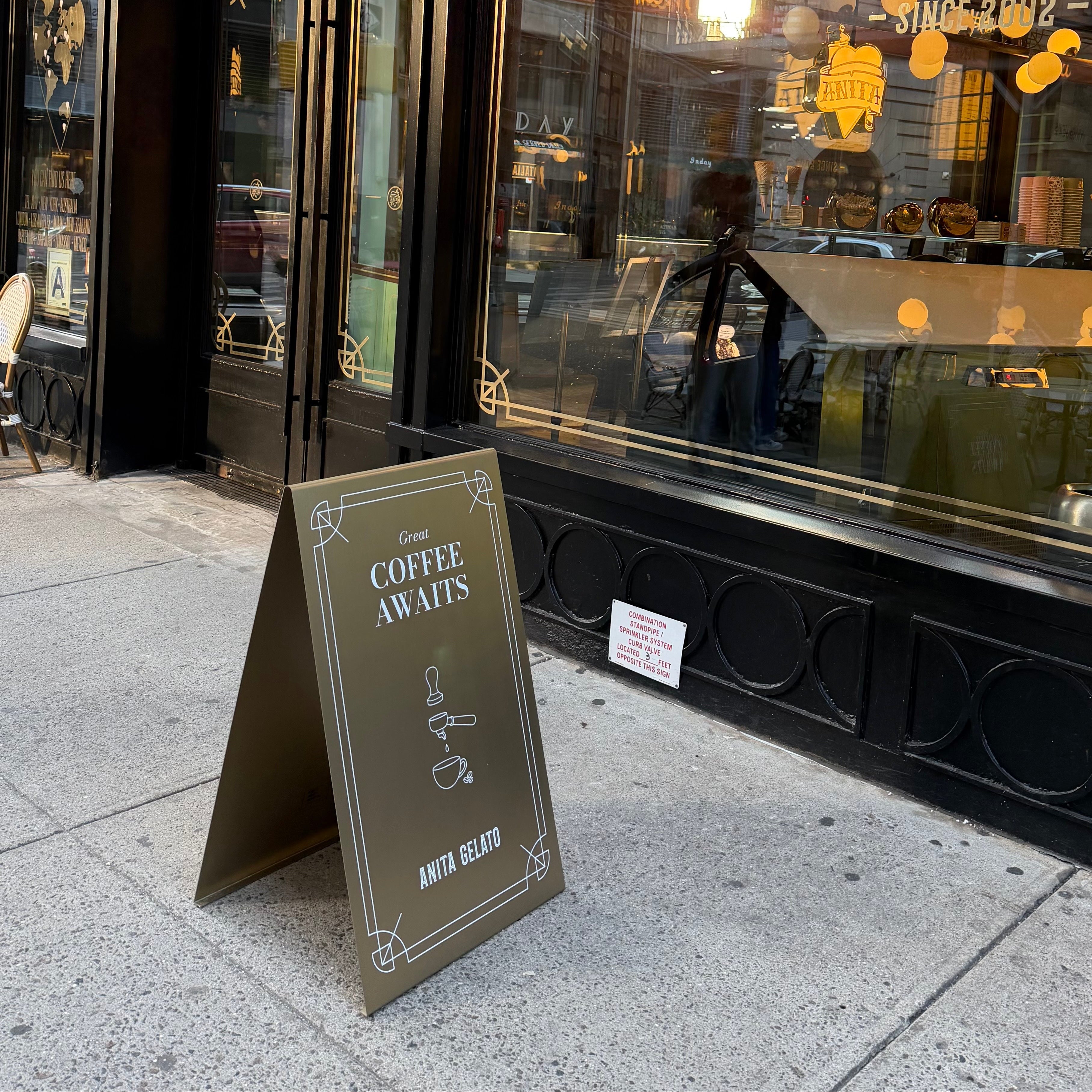 Anita coffee shop exterior with a sidewalk sign advertising 'Coffee Awaits'.