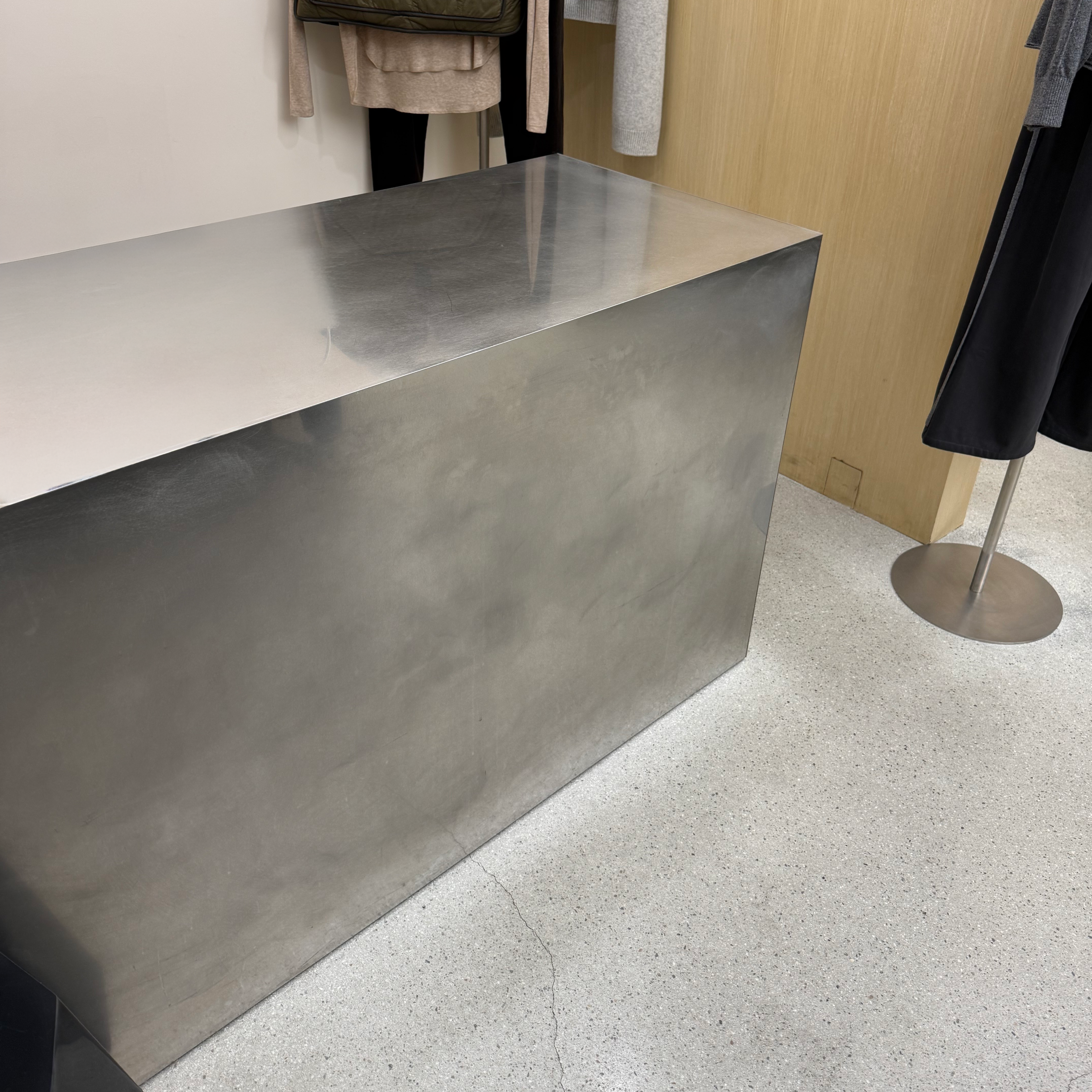 Metal reception desk in a modern interior setting with clothing on display.