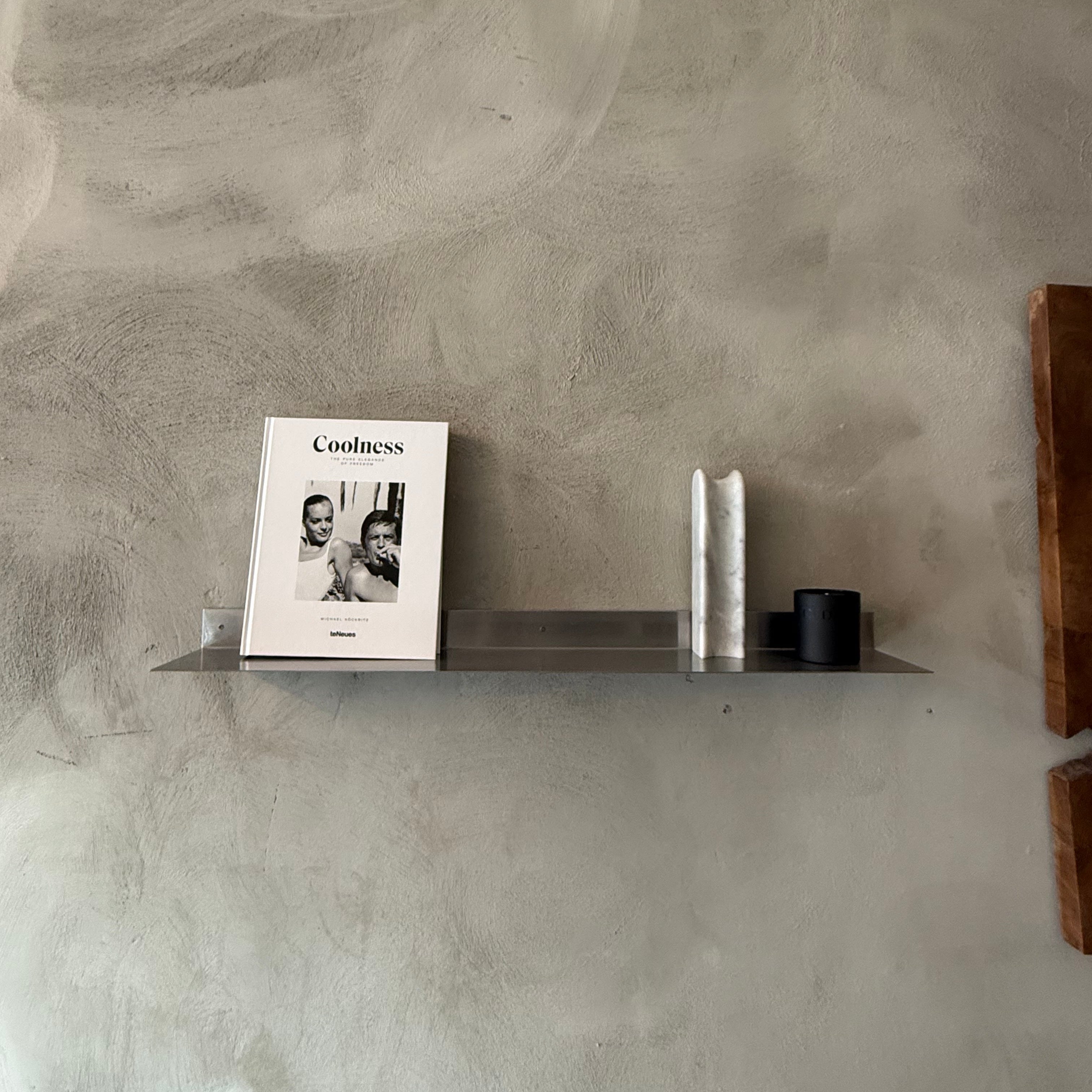Shelf with a magazine and decorative items against a textured wall
