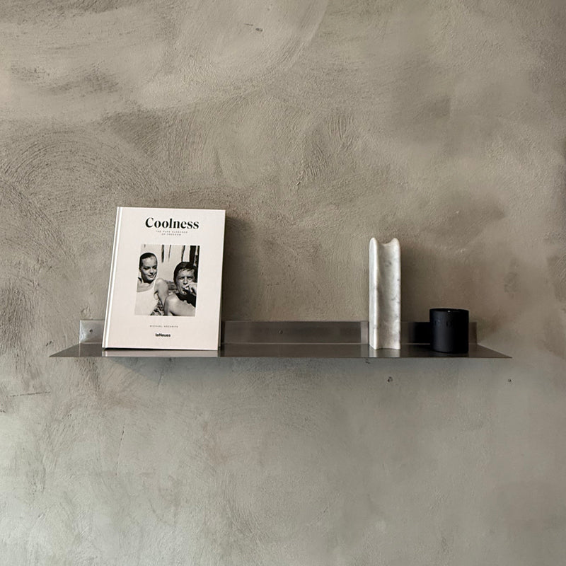 Shelf with a magazine and decorative items against a textured wall