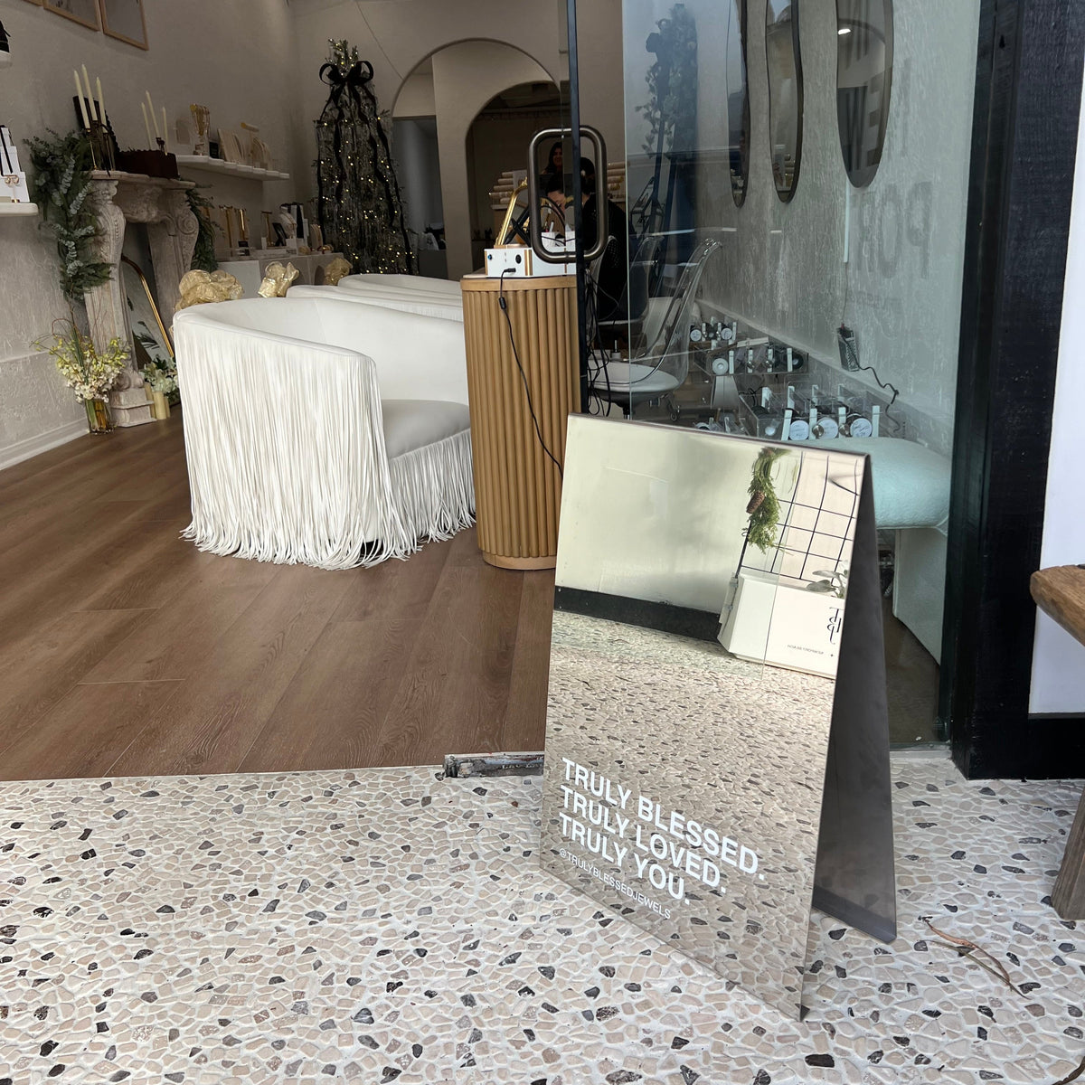 Mirrored A-frame sign at the entrance to a furnished retail space.
