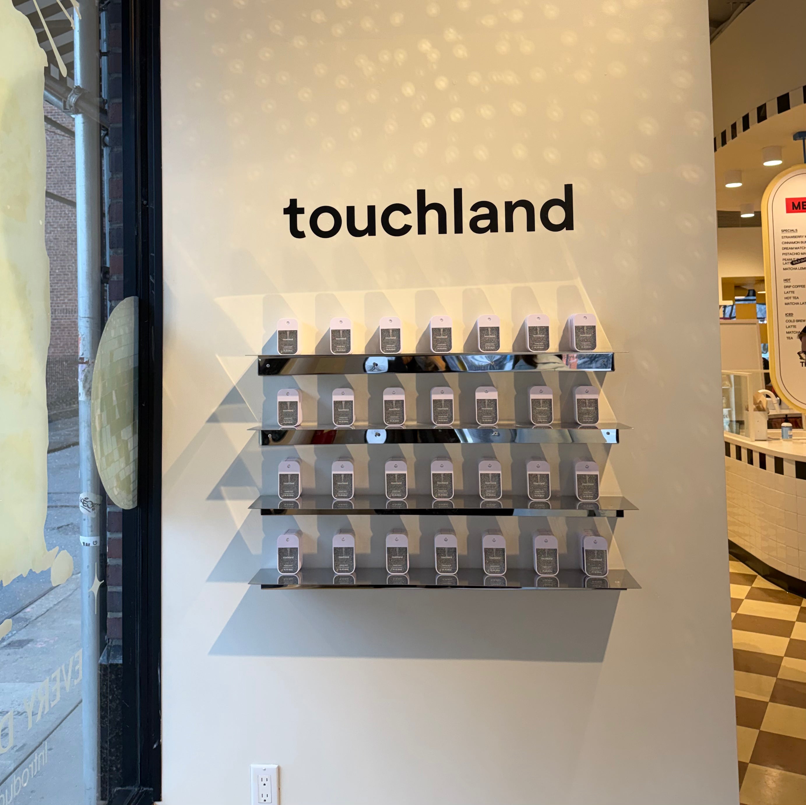 Stainless steel wall shelves displaying Touchland products beneath the brand name.