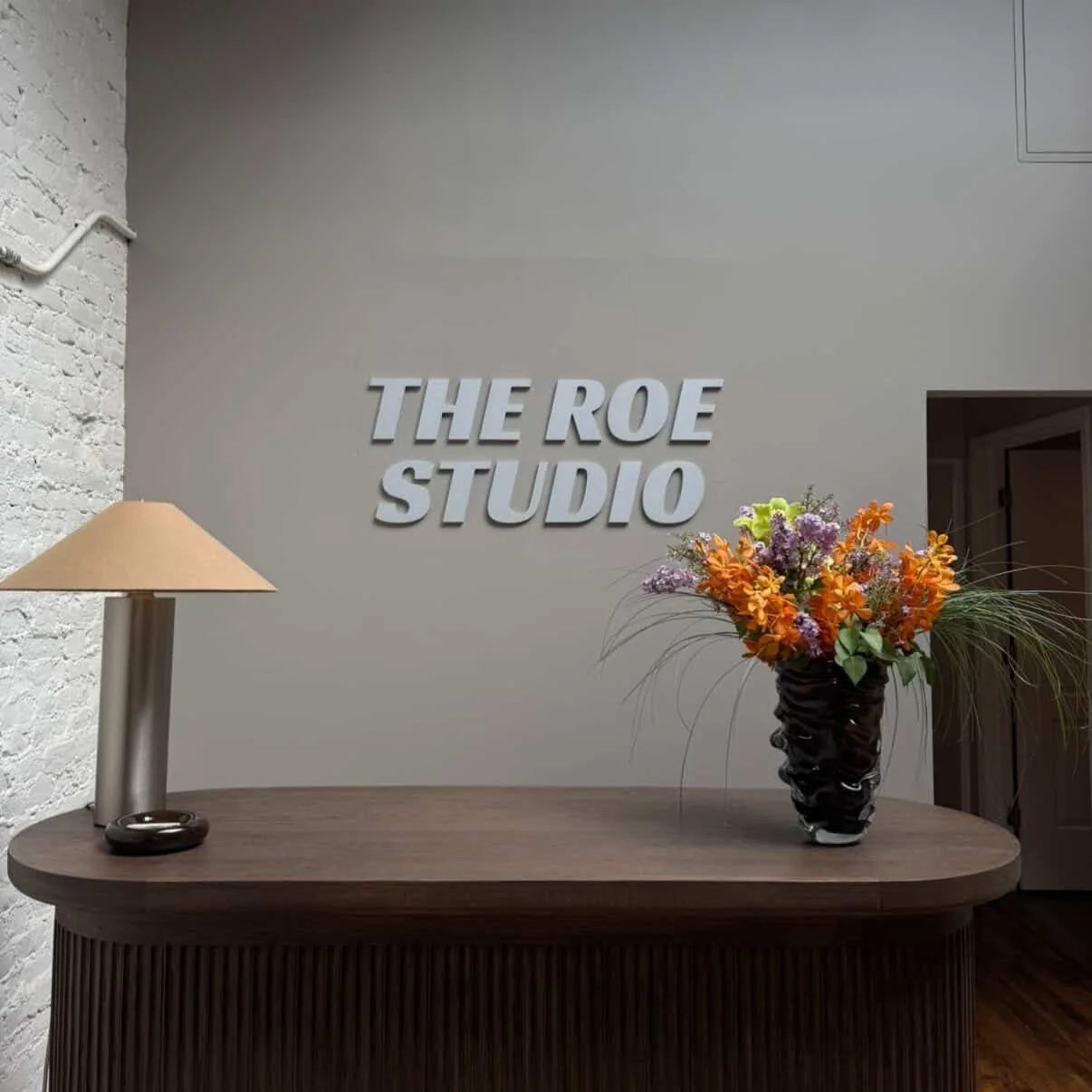 Metal The Roe Studio lettering above a reception desk with flowers.