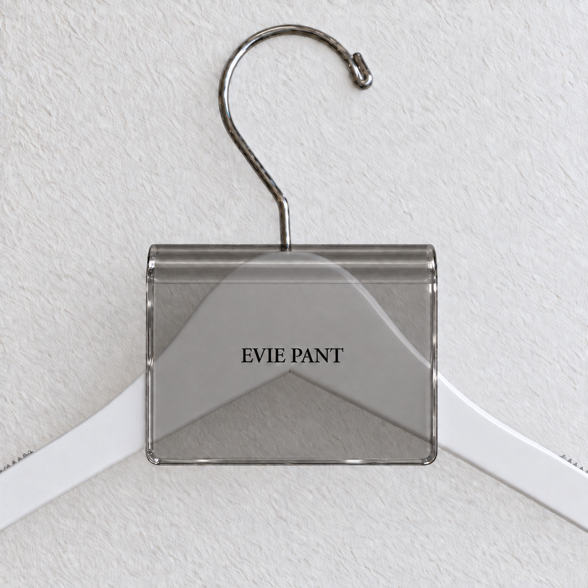 Gray Smoke acrylic hanger sign clip resting on the rounded crown of a white wooden hanger, with example EVIE PANT print
