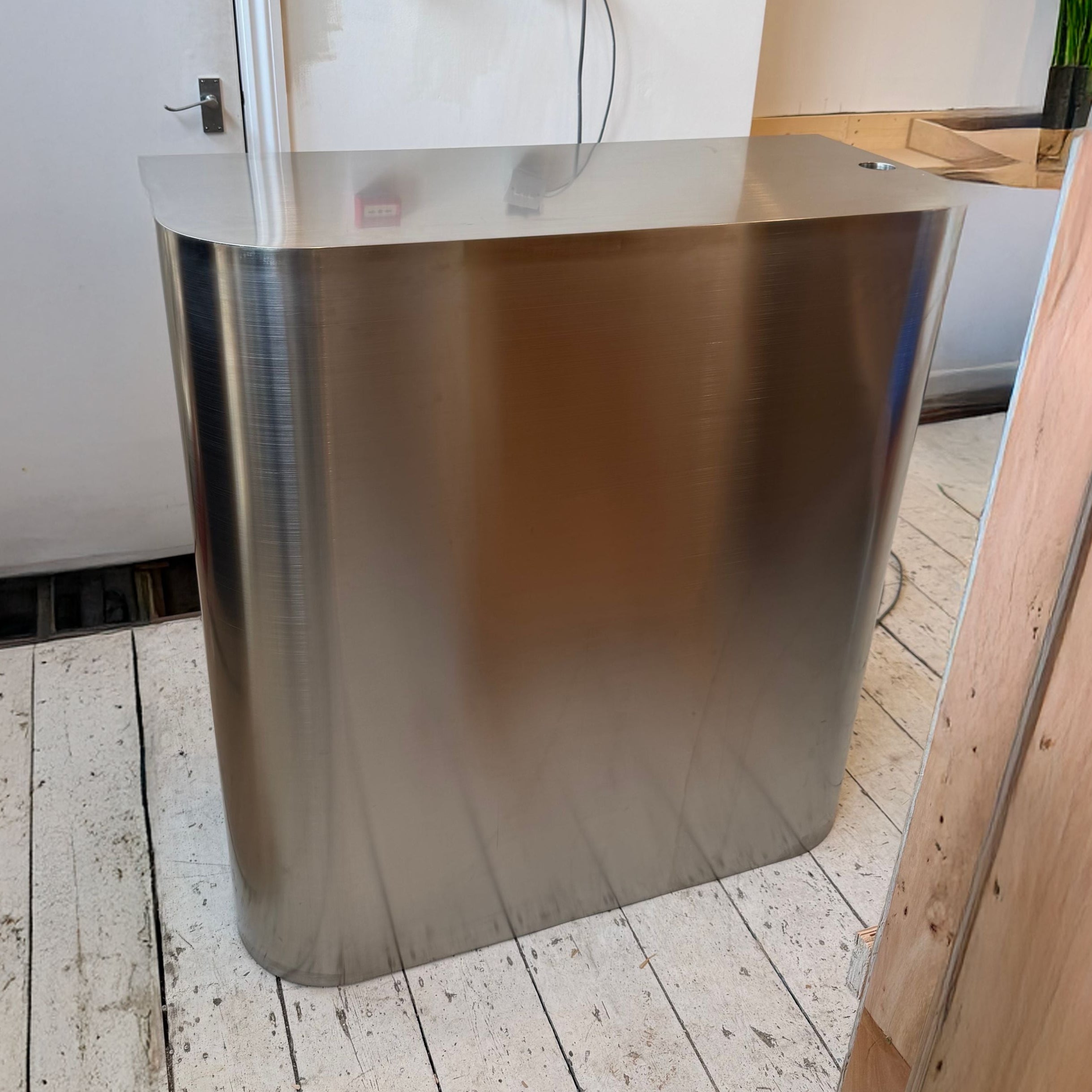 Stainless steel counter against a white wall with a plant in the background