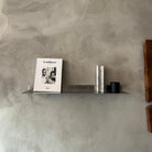 Shelf with a magazine and decorative items against a textured wall