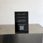 Black acrylic tabletop sign with High Sport lettering and a QR code.