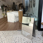 Mirrored A-frame sign at the entrance to a furnished retail space.