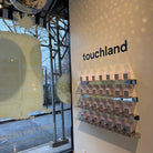 Angled view of stainless steel shelves displaying Touchland products in a shop.