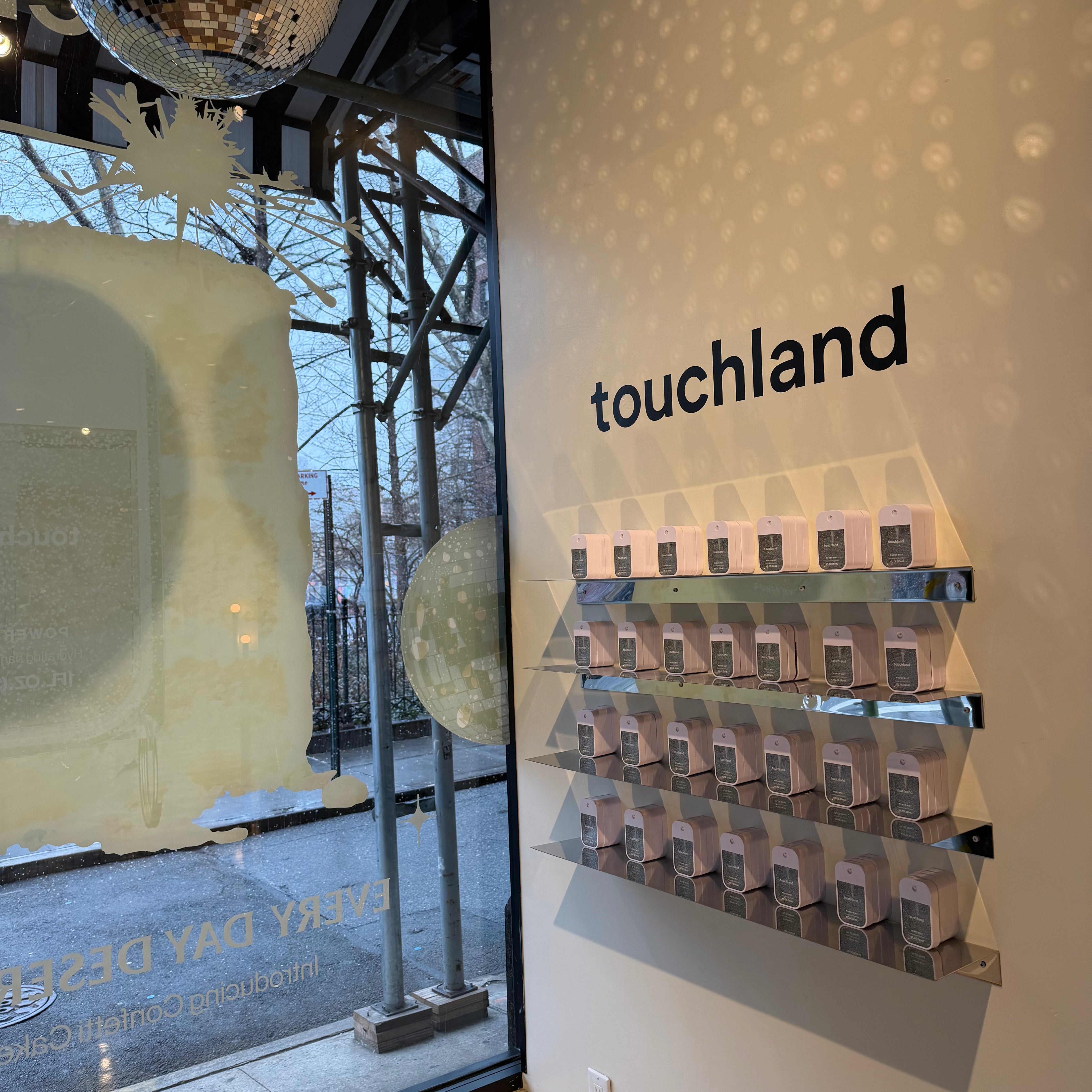 Angled view of stainless steel shelves displaying Touchland products in a shop.