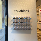 Stainless steel wall shelves displaying Touchland products beneath the brand name.