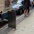 Stainless steel upright sign with Orior lettering beside a parked ice cream truck.